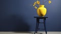 Vivid Contrasts: Lush Lemon Tree in a Sunny Yellow Pot with a Blue Stool Against a Dark Wall. Royalty Free Stock Photo