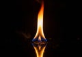 A vivid flame rises from a flat, reflective surface against a dark background. The flame displays a Royalty Free Stock Photo
