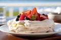 A vivid image of a berry-topped Pavlova against a sunny Australian Christmas beach scene. Royalty Free Stock Photo