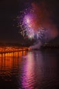 Vivid multicolour fireworks with red and purple sparks on dark sky with reflection in the lake. Fun and joyful holiday background Royalty Free Stock Photo