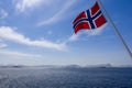 Vivid Norwegian flag billows against a summer sky, with snowy mountains Royalty Free Stock Photo