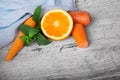 Vivid orange, slices of carrot and sappy green leaves of mint on a light wooden background. Royalty Free Stock Photo