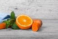 Vivid orange, slices of carrot and sappy green leaves of mint on a light wooden background. Royalty Free Stock Photo