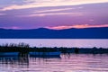 Vivid pink sunrise over calm lake and silhouette of rowing boats. Royalty Free Stock Photo