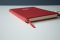 Vivid red notebook closed on white table with colored background Royalty Free Stock Photo