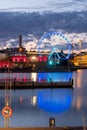 Vivid skyline of the Helsinki downtown district during the sunrise with illuminated Helsinki Sky Wheel in the background.