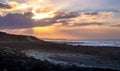 Vivid sunset over volcanic lava landscape on Lanzarote island in Spain. Dramatic sky with last sun rays on cloudy sky