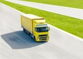 Vivid yellow truck in motion under bright sun