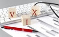 VIX written on a wooden cube on the keyboard with chart on grey background