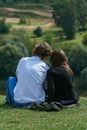 Young couple in love resting on the green hill. People relaxed in the park.