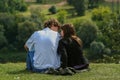 Young couple in love resting on the green hill. People relaxed in the park.