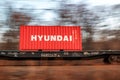 Hyundai inscription on a container moving on a railway trolley against the background of the autumn landscape of Russia in the Far