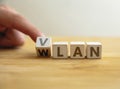 Vlan to wlan network type concept. Finger flips letter at wooden cube changing the word vlan to wlan Royalty Free Stock Photo