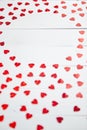 Vlentine`s Day composition. Heart shaped sequins placed on white wooden table