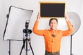 vlogger standing holding blackboard overhead with lighting equipment Royalty Free Stock Photo