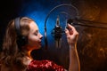 Vocalist singing in the studio. School and vocals. Against the backdrop of blue and orange smoke Royalty Free Stock Photo