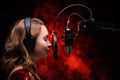 Vocalist singing in studio. School and vocals. Against the backdrop of red smoke Royalty Free Stock Photo