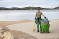 Young woman cleaner, working for city service, on her morning duty routine cleaning the beach in Vodice, Croatia