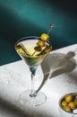 Vodka martini, classic alcoholic cocktail drink with vodka and vermouth, green olives garnish, dark background, bright hard light Royalty Free Stock Photo