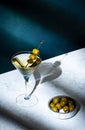 Vodka martini with olives, alcoholic cocktail drink with vodka and vermout, dark green background, bright hard light and shadow Royalty Free Stock Photo