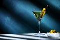 Vodka martini with olives, alcoholic cocktail drink with vodka and vermouth, dark green background, bright hard light and shadow Royalty Free Stock Photo