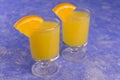 Vodka with orange juice in small glasses on a blue background. Royalty Free Stock Photo