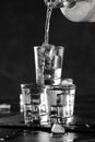 Vodka in shot glasses pouring out of the bottle on black stone background, iced strong drink in misted glass Royalty Free Stock Photo