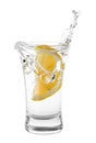 Vodka splashing out of shot glass with lemon on white background Royalty Free Stock Photo