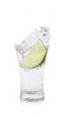 Vodka splashing out of shot glass with lime on white background Royalty Free Stock Photo