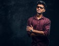 Vogue, fashion, style. Handsome young Indian guy wearing a stylish shirt and sunglasses posing with crossed arms. Royalty Free Stock Photo