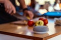 Voice controlled smart speaker on a coffee table. Man cutting vegetables in background. Royalty Free Stock Photo