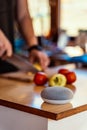 voice controlled smart speaker in a interior kitchen. Man cutting vegetables in background. Royalty Free Stock Photo