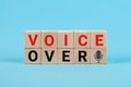 Voice Over Word on Block Letter Tiles and Microphone on wooden cubes. Conceptual Image on Blue Background