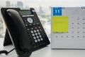 VOIP IP phone for conference call meeting in November calendar with sticky note of appointment reminder on office desk