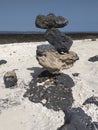 Volcanic black rocks stacked like a pyramid in the sand. Stones of different sizes and shapes stacked and balanced. Apacheta or Royalty Free Stock Photo