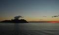 A smoking volcanic island at sunset.