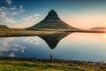 Volcanic Kirkjufell mountain with lake reflection and traveler man standing during sunrise at Iceland Royalty Free Stock Photo