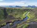 Volcanic landscape with mountains of Tindfjallajokull glacier massif, green hills and blue creek water with lush moss