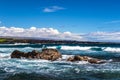 Volcanic rock, ocean and surf; Punaluu Black Sand Beach in Hawaii. Clouds and sky in background; shoreline in distance. Royalty Free Stock Photo