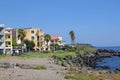 Volcanic stones on the seashore, large volcanic rocks by the Ionian sea, seashore, palm trees by the sea, houses right on the seas Royalty Free Stock Photo