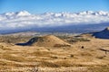 Volcano crater with copy space on a cloudy horizon. High angle view of an empty barren nature scene of desert grass