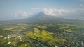 Volcano erupt at countryside cityscape aerial. Urban cottages with traffic road at green valley