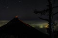 Volcano fuego erupting in nightsky with stars and a tree in the forground