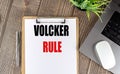 VOLCKER RULE text on clipboard paper with laptop, mouse and pen