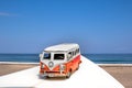 Camping Car On A White Surfboard At The Beach With A Blue Ocean.