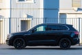 Volkswagen Touareg R- Line SUV car parked near fence and wall of industrial building, side view