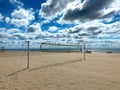 Volleyball court with a volleyball net on a sandy sea beach against a blue sky with fluffy clouds Royalty Free Stock Photo