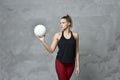 Volleyball girl hold and kick ball in black costume on grey concrete wall background