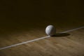 Volleyball On Hardwood Court Floor With Spot Lighting