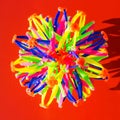 Volumetric multi-colored ball made of plastic sticks on a red background. Square photo. Top view, flat lay. Abstract geometric